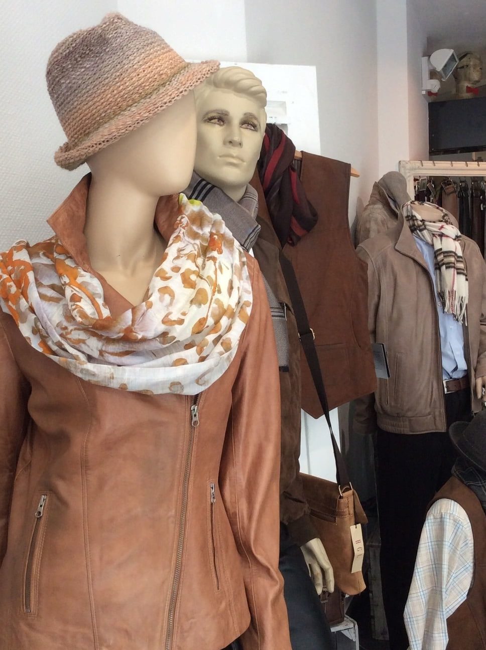 EIne braune Lederjacke für die Damen in Kombination mit einem in verschiedene Brauntönen gehaltener Hut und einem Halstuch