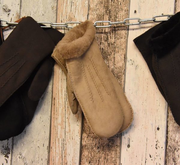 Lammfellhandschuhe in hellem braun an einer Metallkette an der Wand