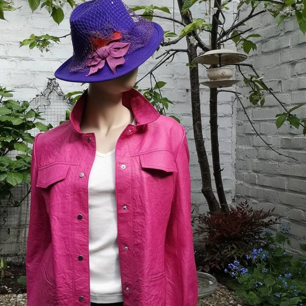 Ein violetter Hut mit Fischernetz und Schleife in Kombination mit einem pinken Lederhemd