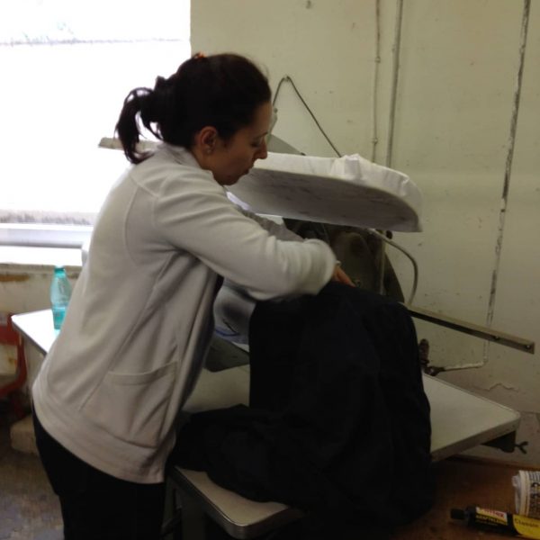 Eine Frau bügelt eine Lederjacke von Hand