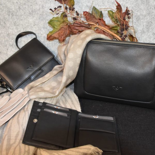 Schwarze Ledertasche mit einem schwarzen Lederportemonnaie und einer schwarzen Lederumhängetasche. Ansehnlich dekoriert mit einem hellen Schal, creme-weißen Lederhandschuhen für Frauen